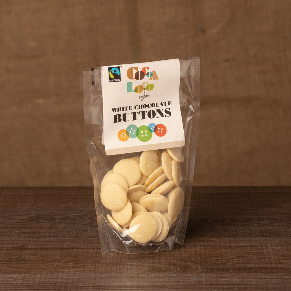 
                  
                    A packet of white chocolate buttons, with the Cocoa Loco label, on a dark wood counter with a brown background
                  
                